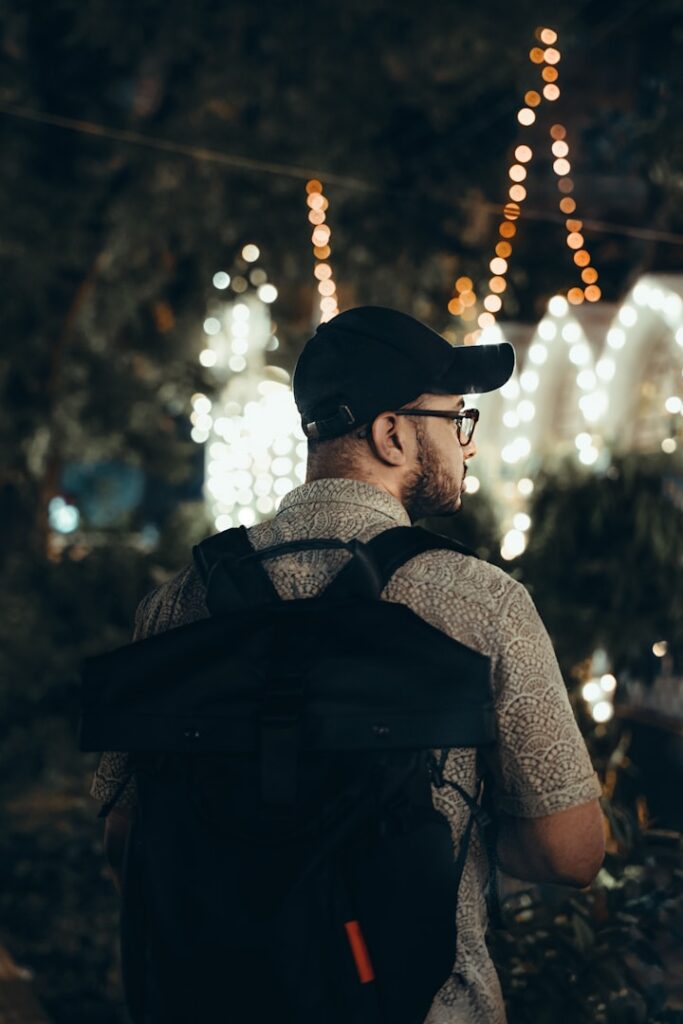 A man with a backpack is looking at a christmas light display