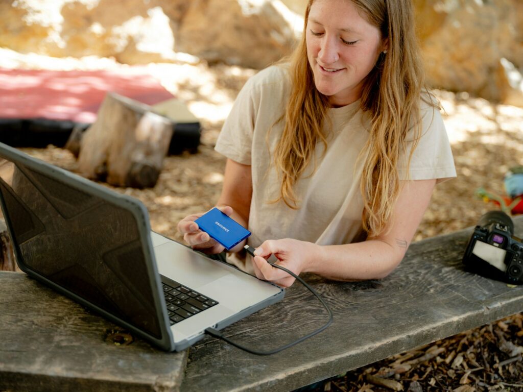 A woman sitting at a table with a laptop and a cell phone