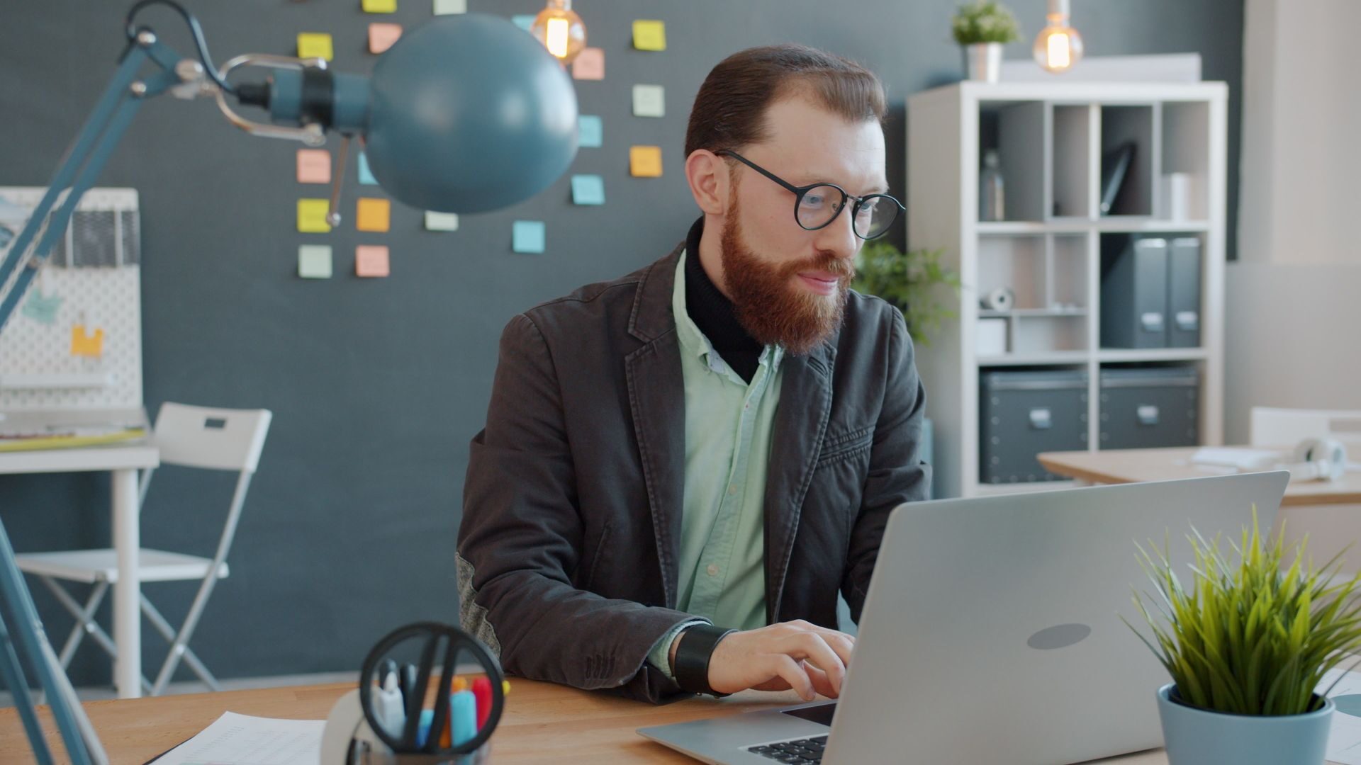 A year-round tax strategy for agencies helps owners plan for estimated taxes, protect cash flow, understand profitability, and avoid unpleasant tax surprises.. Businessman focuses on laptop in trendy office space with notes.